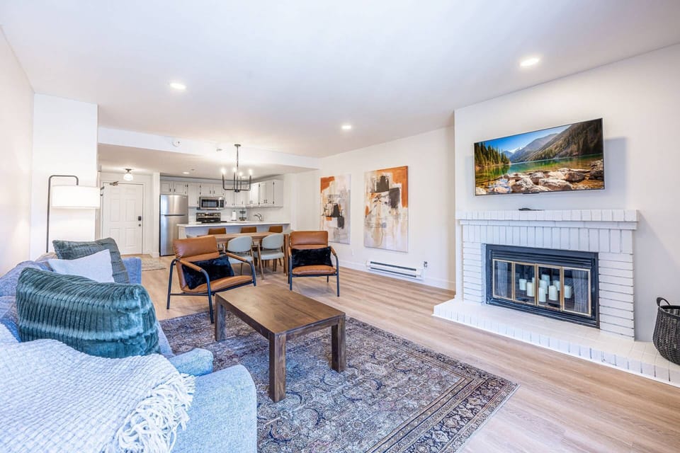 Living room with comfortable seating and TV, open to the kitchen and dining area. (alternate angle, looking back towards kitchen from living room)