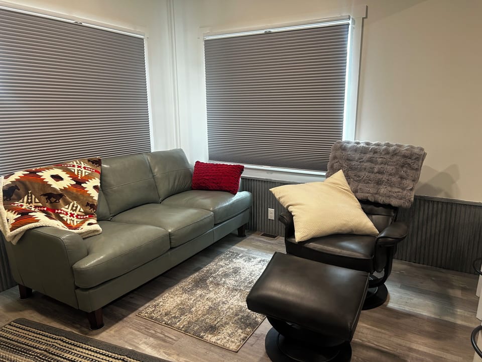 Living room area with large leather couch and swivel rocking chair.