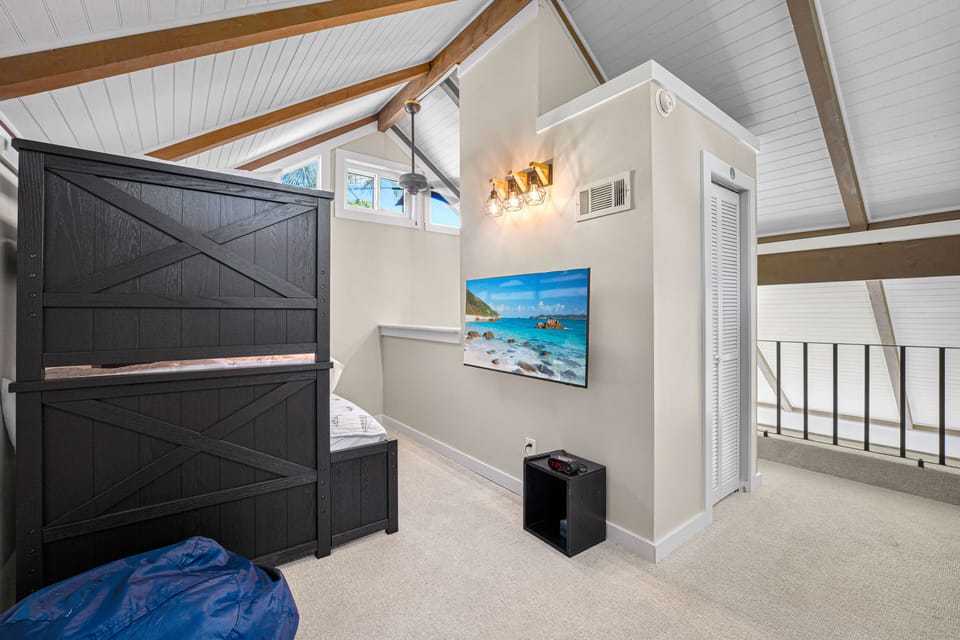 Charming loft space with bunk beds, vaulted ceilings, and a wall-mounted TV—perfect for kids or extra guests.