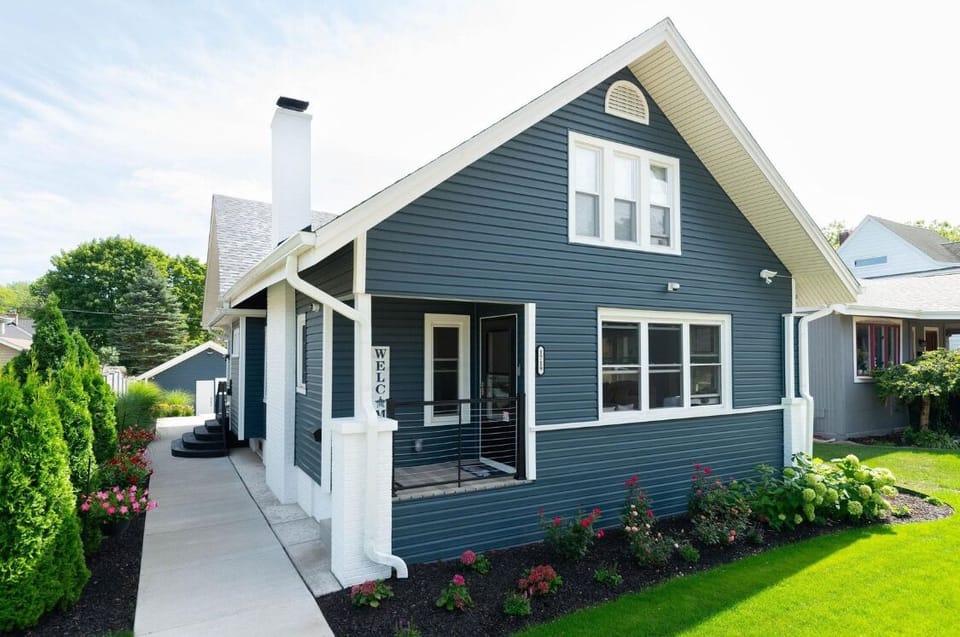 Welcome to Post Ave: dark blue siding, white trim, private entrance, bright windows, and charming la