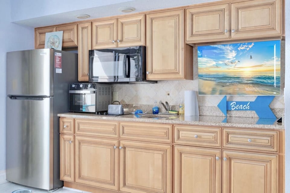 Kitchen with oceanfront views, fully stocked with a full-size fridge, cookware, silverware, dinnerware, microwave, 2-burner stovetop, toaster, and Keurig with K-Cup and drip coffee maker.