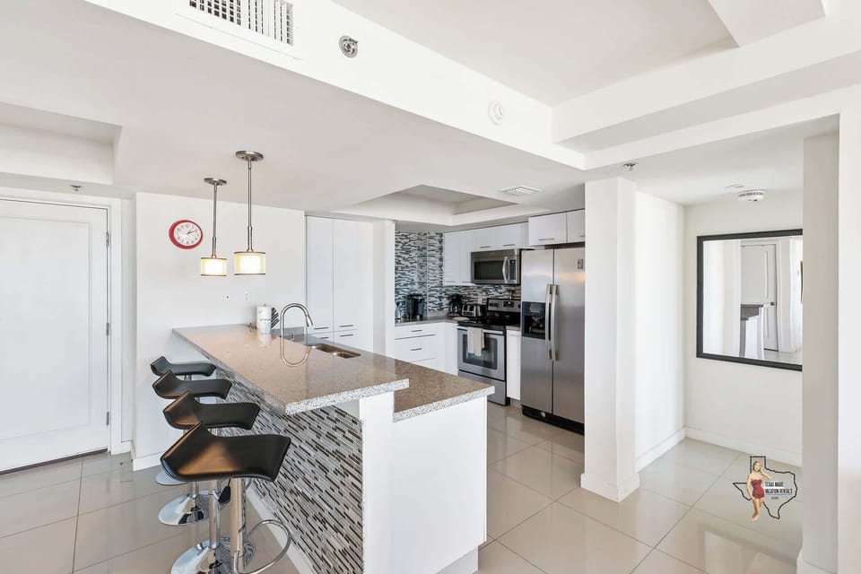 Fully equipped kitchen featuring an island and sleek barstools for casual dining.