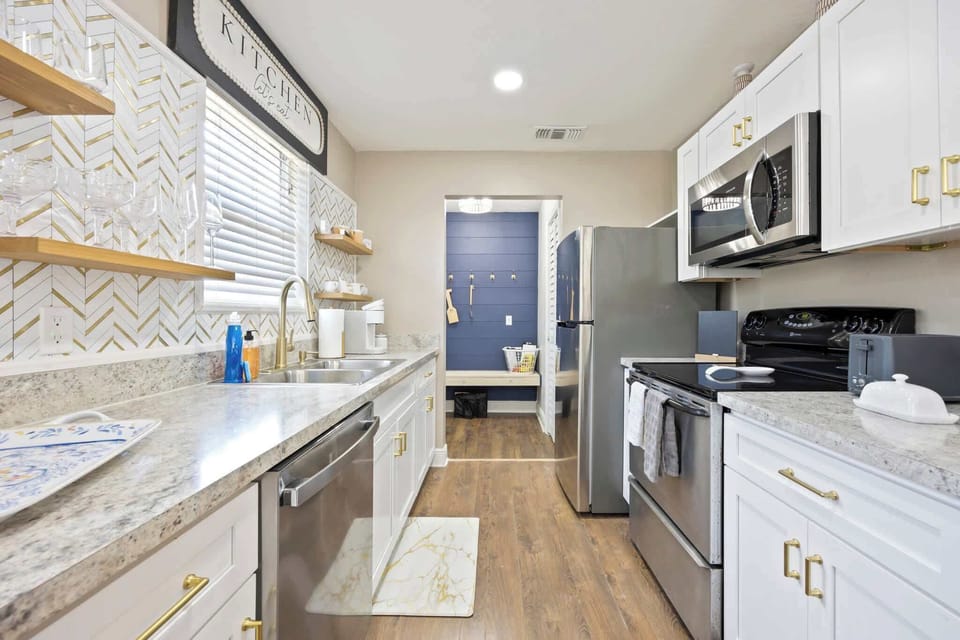 Modern kitchen with stainless steel appliances and gold-accented cabinetry.