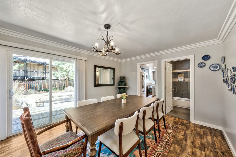 Your elegant dining room features a spacious table for eight, charming antler chandelier, and sliding doors opening to your private outdoor space.