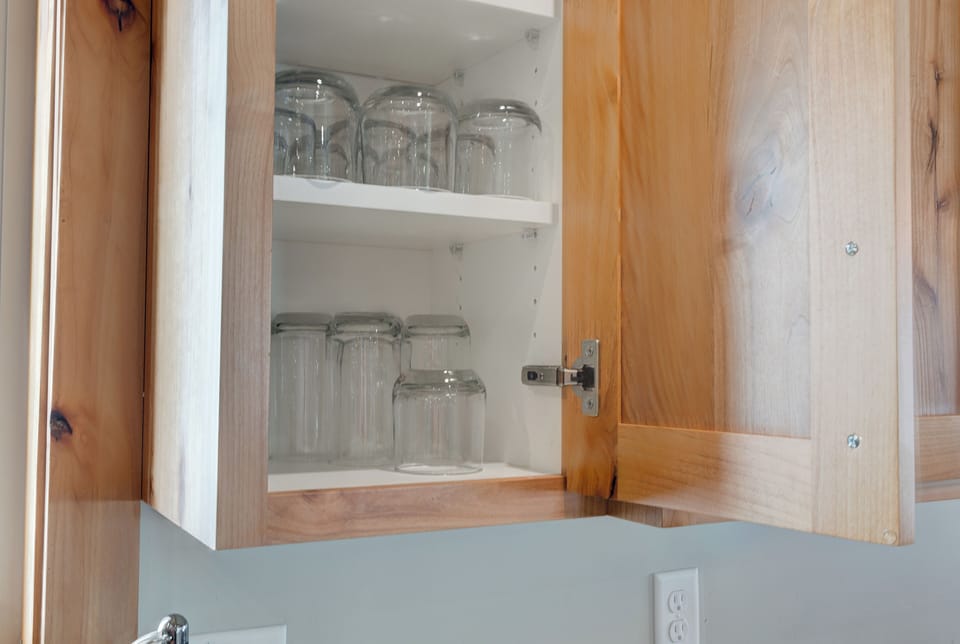 A cabinet storage with glassware neatly arranged—simple, tidy, and guest-ready.