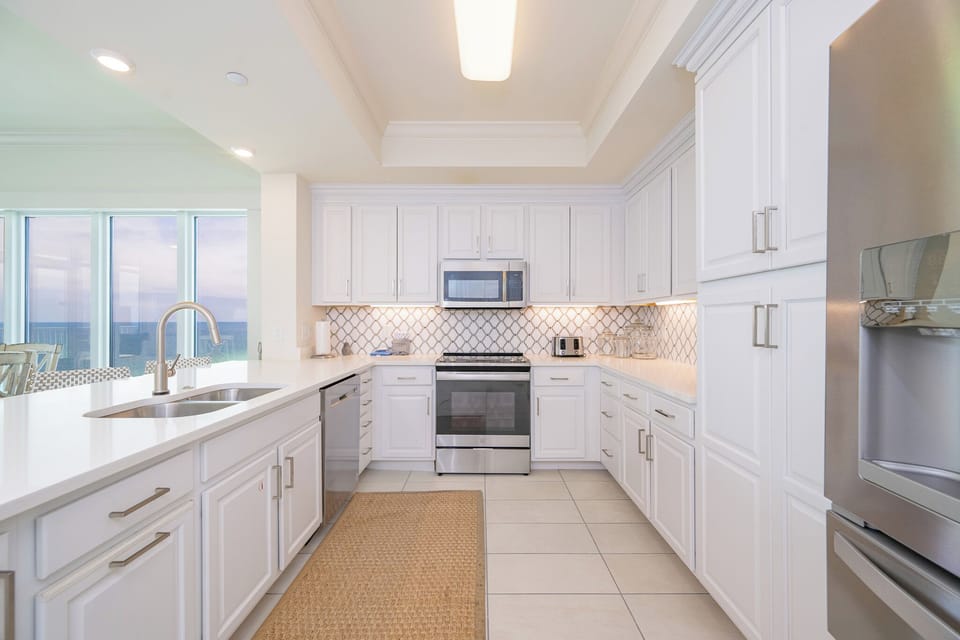 You prepare fresh family meals in a bright kitchen filled with soft light and beach views 