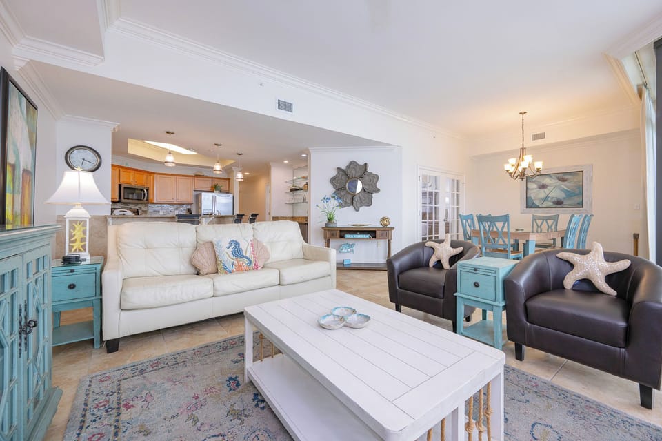 Bright and inviting living room featuring comfortable seating, a large TV, and an open view into the modern kitchen