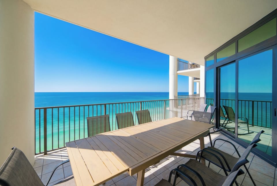 Enjoy meals with an impressive view from this spacious balcony featuring a large wooden dining table and comfortable chairs