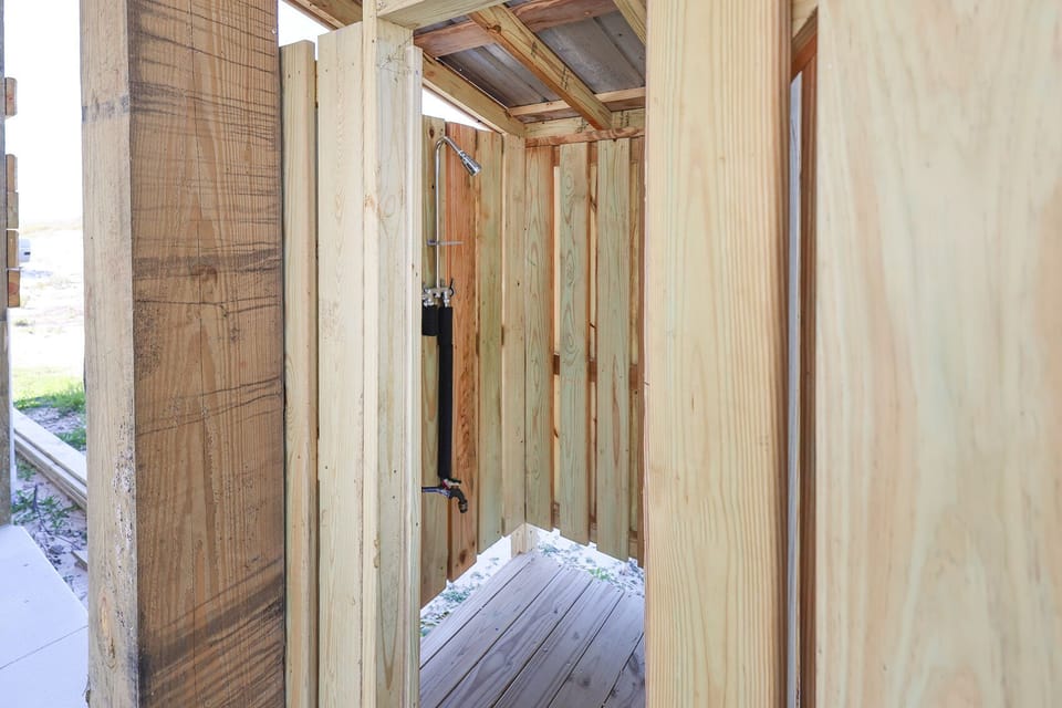 This outdoor shower features natural wood finishes and provides a refreshing experience after a day at the beach