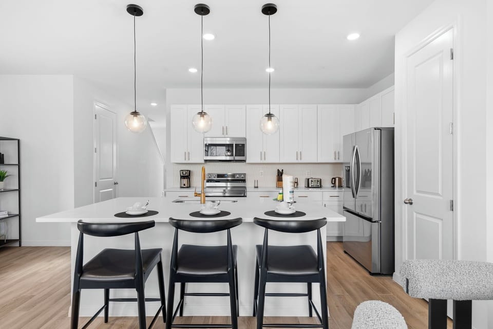 White cabinets, stainless steel appliances, and black barstools.