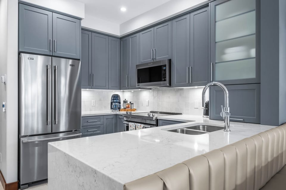 This modern kitchen becomes the heart of any gathering, offering a perfect balance of sleek design, comfort, and guest-focused functionality.