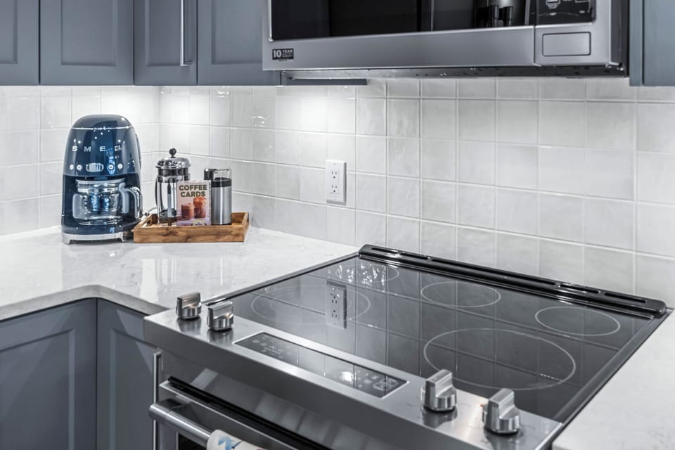 New appliances, a spice rack, & beautifully displayed cookbooks inspire culinary exploration. A set of high-quality knives, cutting boards, and other essentials ensures that everything is ready for guests to prepare their meals. 