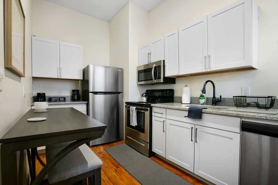 Bright kitchen w/ stainless steel appliances, white cabinets & breakfast bar seating