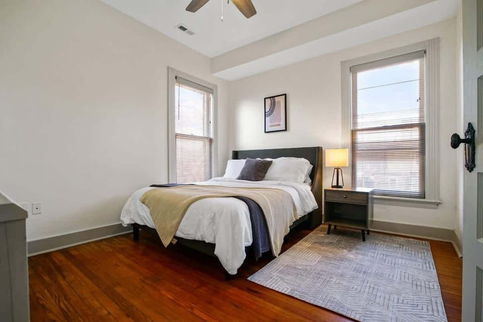 Peaceful bedroom w/ ceiling fan, soft linens & large windows for a calm retreat