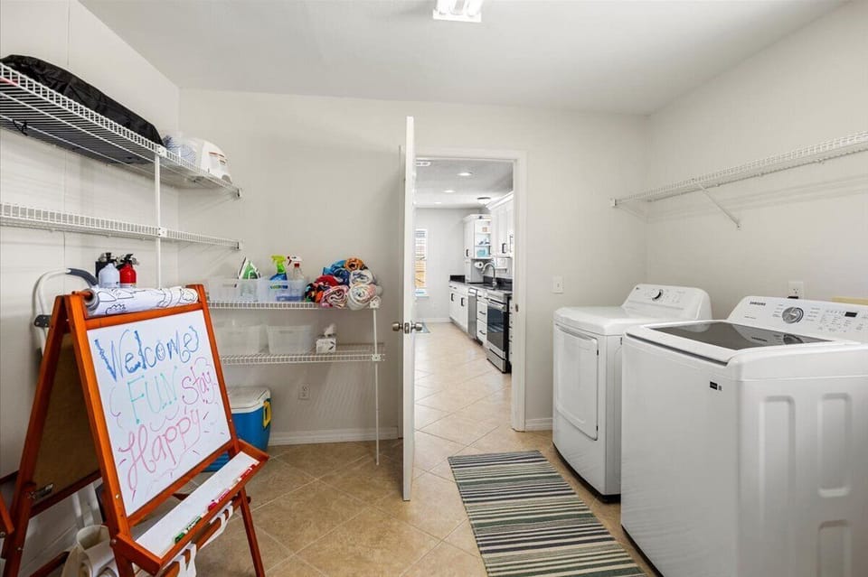 Laundry room with pack n play, booster, art easel, cooler, beach towels.