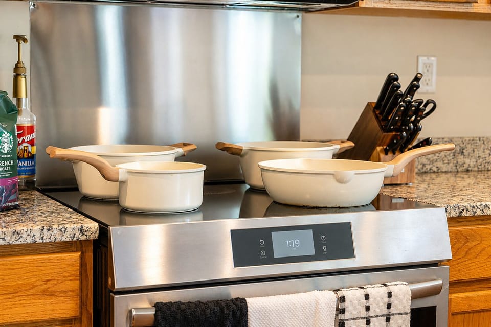 Well-stocked kitchen with modern stove, granite counters, and stylish cookware