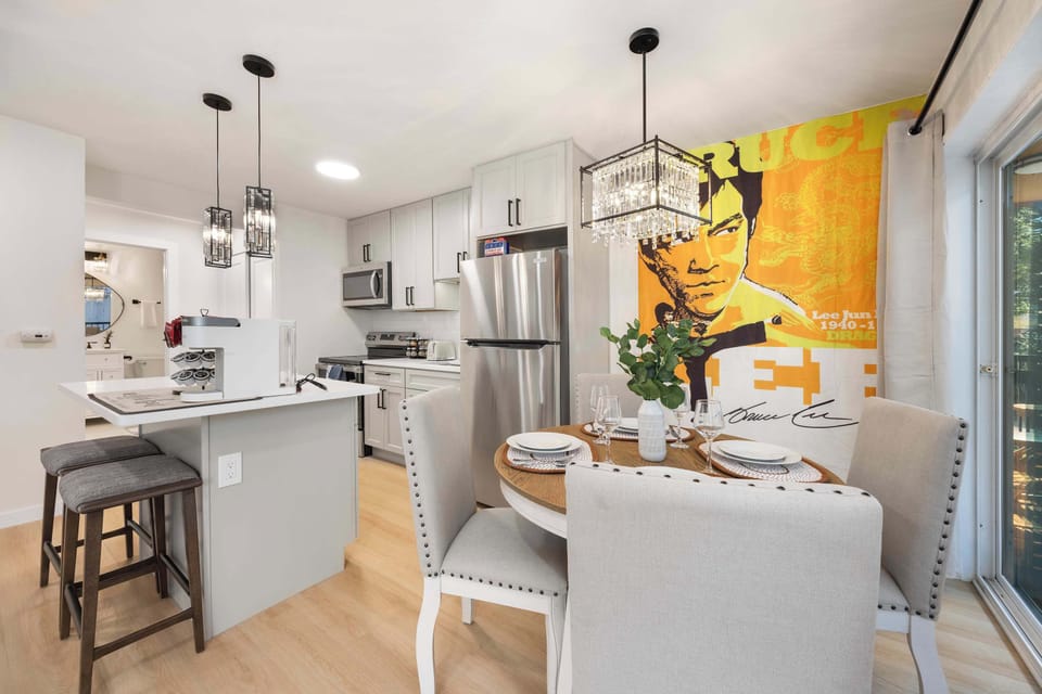 Dine in style in this modern, well-lit space featuring chic urban décor with a striking pop art centerpiece, sleek kitchen, and a view into the airy outdoor area.