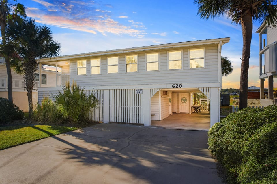 Coastal beach house with tropical landscaping and covered parking area in a peaceful residential neighborhood.