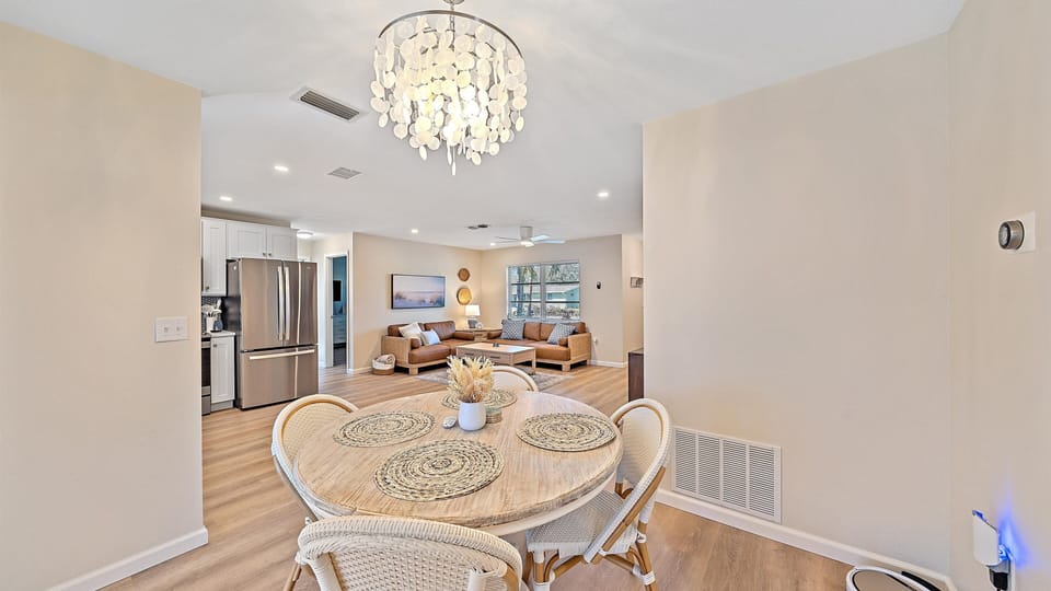 Enjoy seamless open-concept living and dining under a beautiful coastal chandelier, creating a bright and airy space perfect for gathering after a day at Siesta Key Beach.