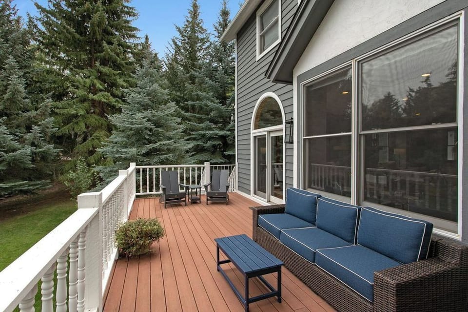 A wooden deck with a dark wicker sofa and blue cushions