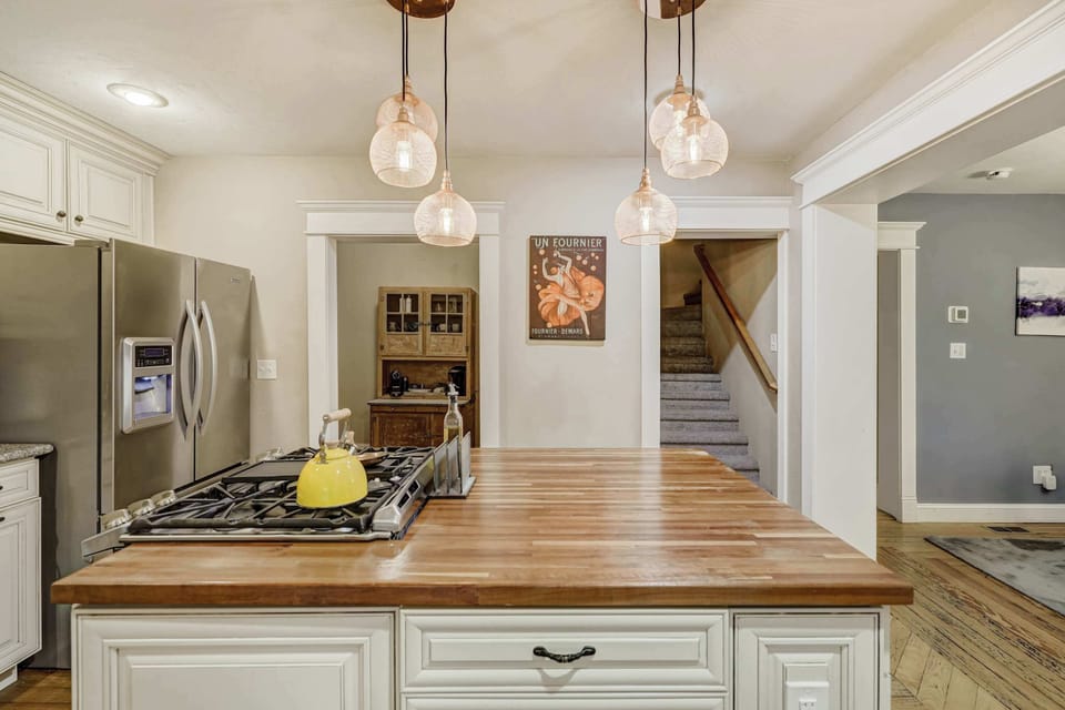Spacious kitchen with sleek stainless steel appliances, a butcher block island, and warm lighting, creating the perfect space for cooking and entertaining.
