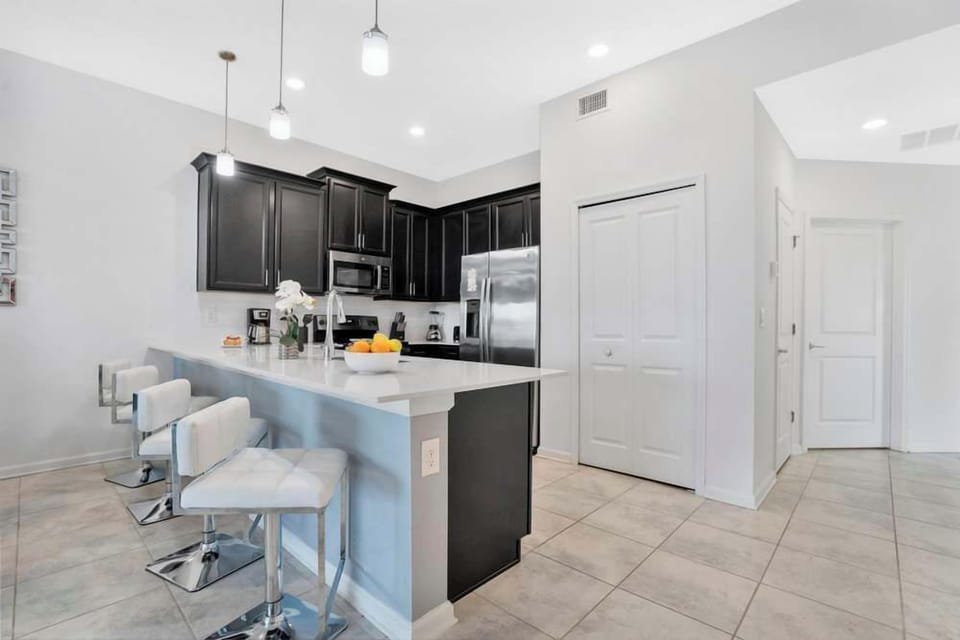 Modern kitchen with black cabinetry and a white quartz breakfast bar with seating.
