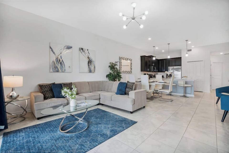 Open-concept living and dining area with modern furnishings and a blue accent rug.