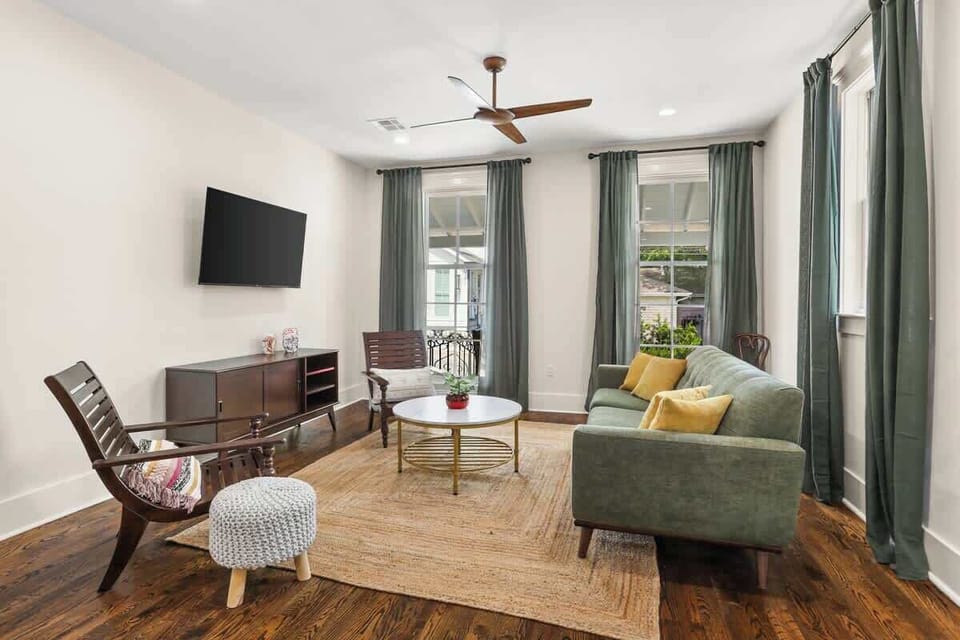 Bright and stylish living room with mid-century accents, flat-screen TV, and plenty of natural light—perfect for relaxing after exploring Magazine Street.