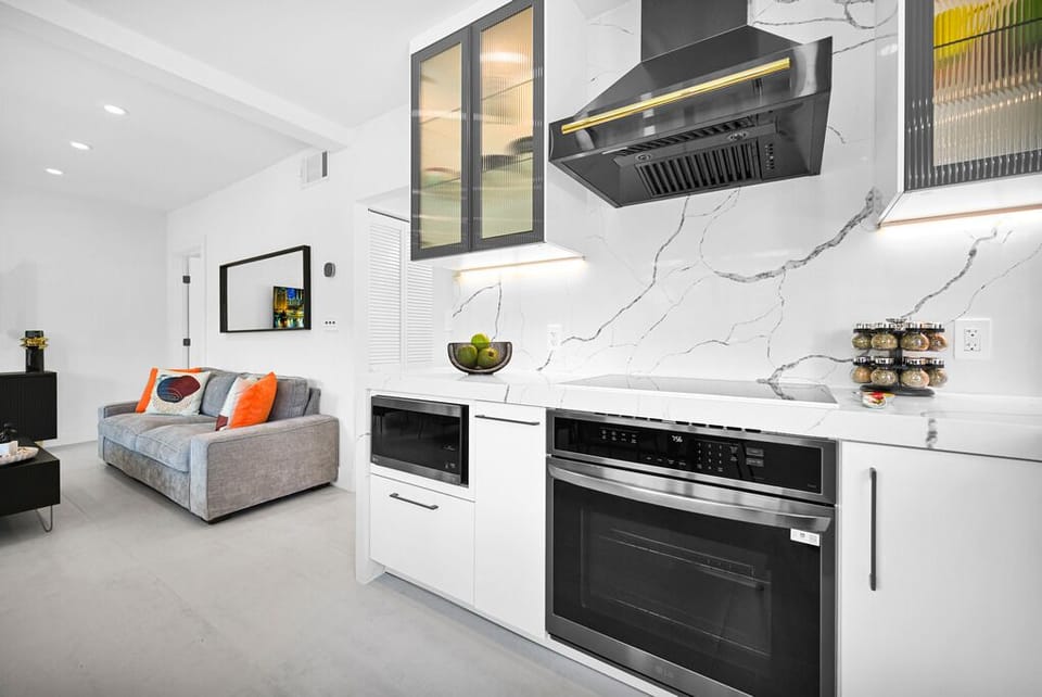 "Modern kitchen with marble backsplash, sleek appliances, and cozy living room."