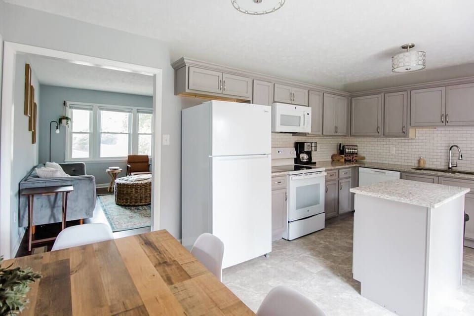 This bright kitchen features white cabinets, countertops, and appliances.