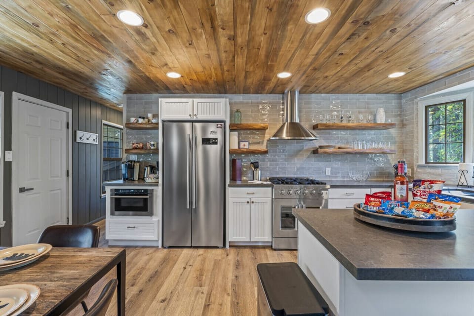 Fully equipped kitchen w/ stainless steel appliances, island seating & rustic finishes.