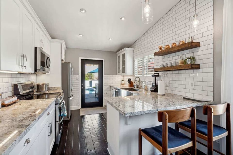 The fully equipped modern kitchen is stocked with all culinary essentials and stainless-steel appliances complete with island bar seating.
