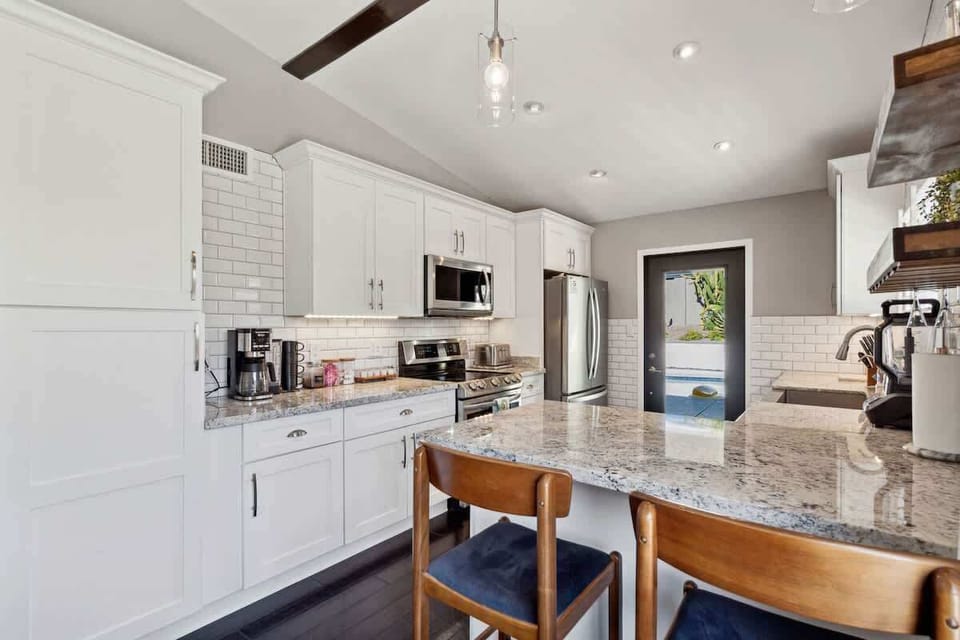 The fully equipped modern kitchen is stocked with all culinary essentials and stainless-steel appliances complete with island bar seating.