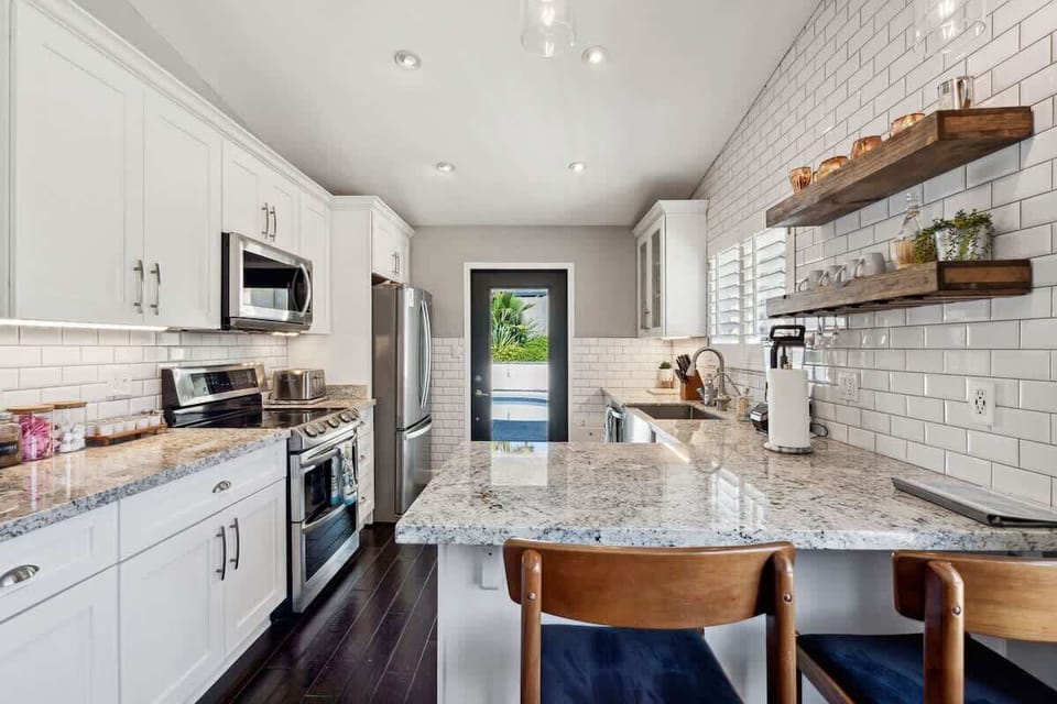 The fully equipped modern kitchen is stocked with all culinary essentials and stainless-steel appliances complete with island bar seating.