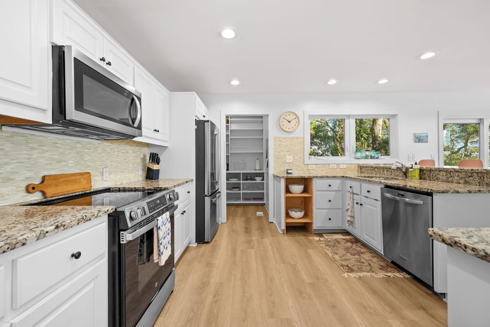 Your spacious kitchen awaits with granite countertops, stainless appliances, and sunny windows overlooking peaceful trees.