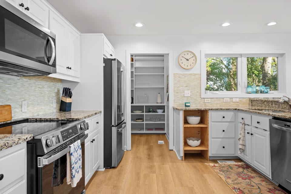 Prepare delicious meals in your fully-equipped kitchen featuring granite counters, stainless appliances, and bright windows overlooking lush greenery.