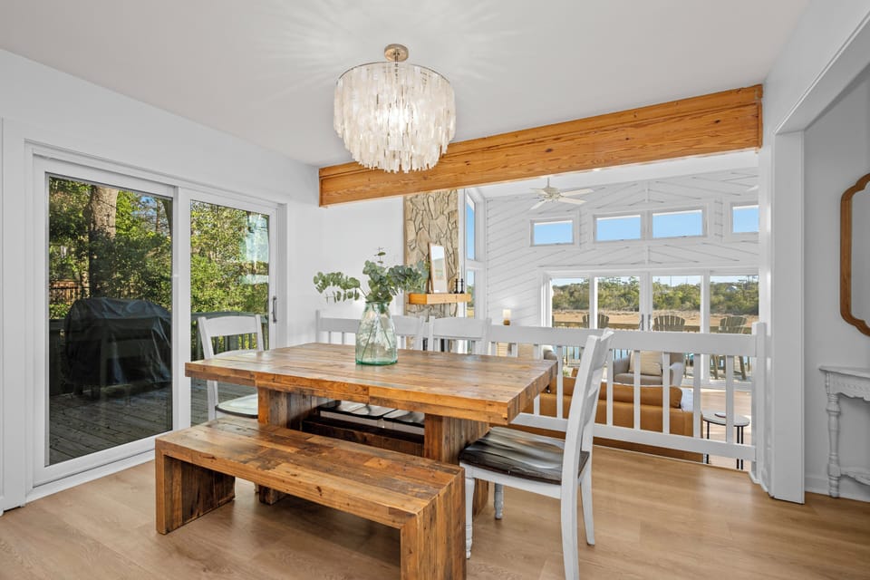 Gather around your stunning rustic dining table beneath an elegant chandelier, with beautiful natural light streaming through large windows.