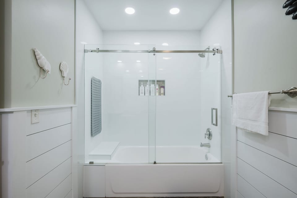 Shower/tub, bath mat, shampoo, conditioner, body wash and shaving cream.
