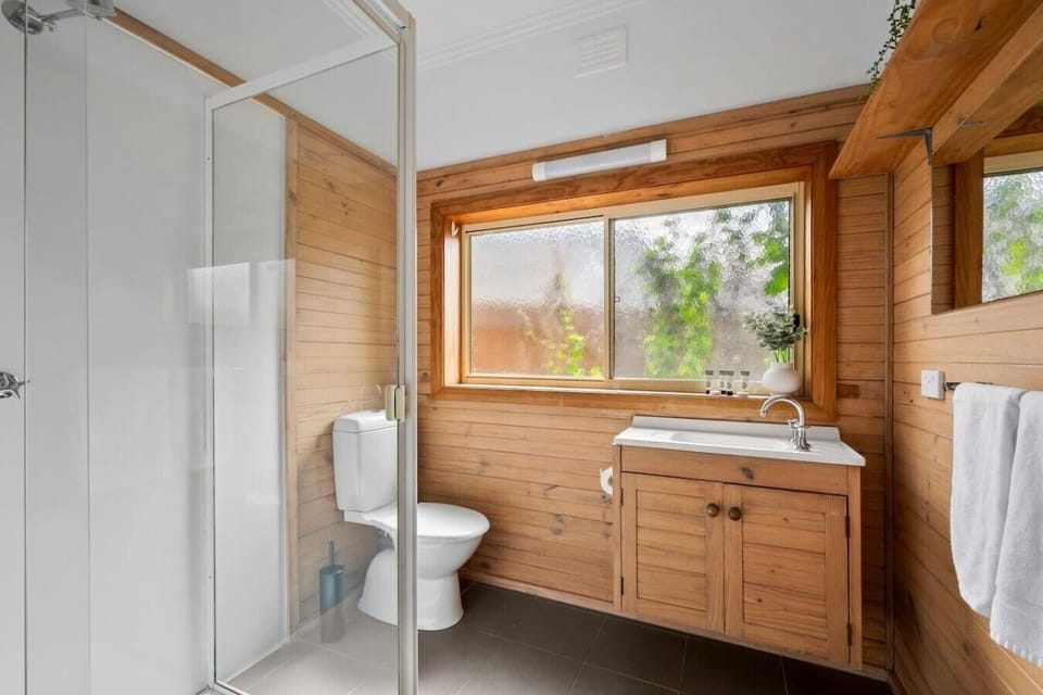 Central bathroom with timber finishes, full-size shower and fresh towels provided.