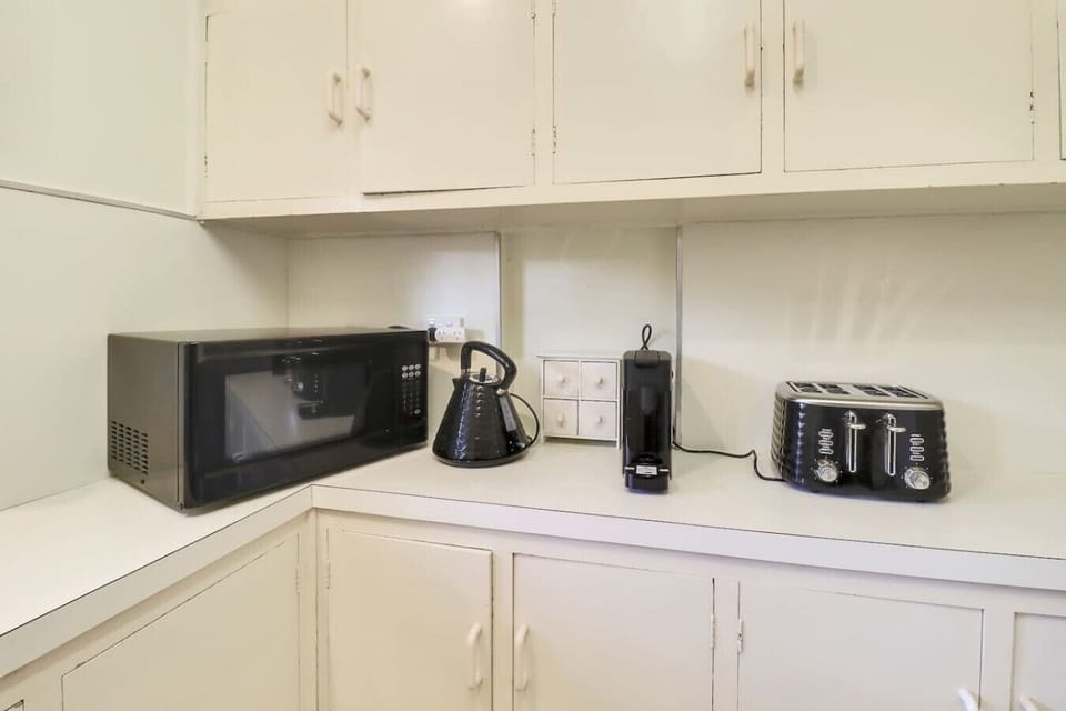 Functional kitchen setup with microwave, kettle and everyday essentials.