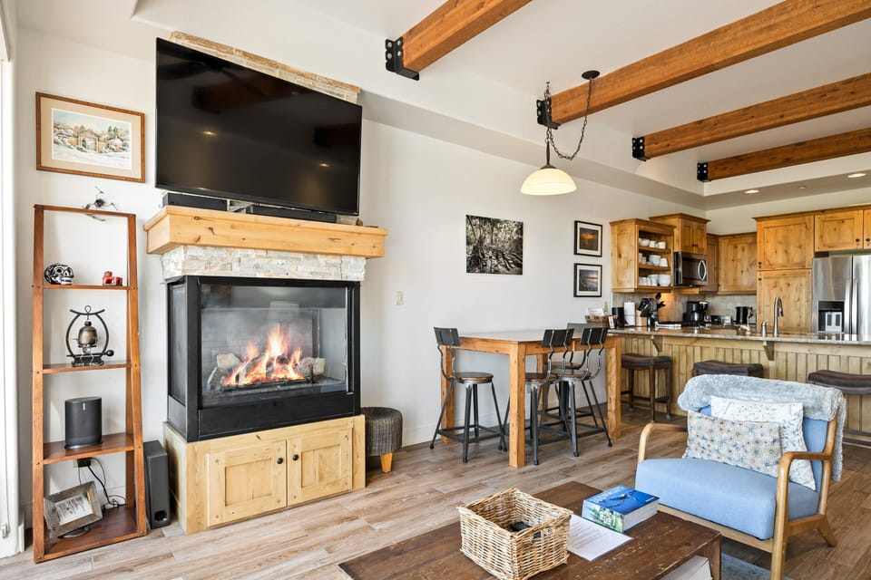 - Cozy living room with warm fireplace glow  
- Rustic beams highlight open-concept design  
- Modern kitchen and dining space for gatherings