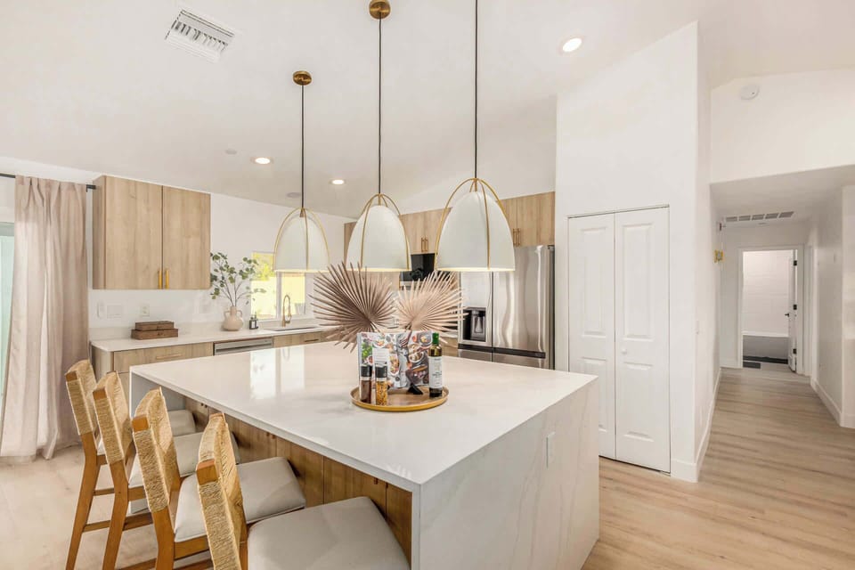 Freshly remodeled kitchen with pearl white quartz conters with waterfall edges and custom pendants