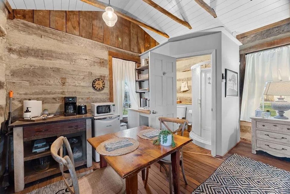 The compact kitchenette provides a microwave, mini refrigerator, coffee station, shelving, and a nearby two-person dining table.