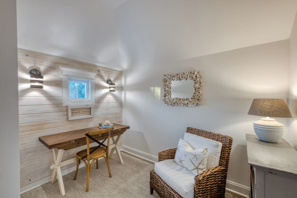 Desk nook with coastal lighting and wicker chair at Pelican’s Pe - Desk Nook – Coastal Workspace with Texture & Charm – Whether you're journaling, charging up, or sneaking in a quick email, this stylish corner workspace at Pelican’s Perch pairs functionality with breezy design.