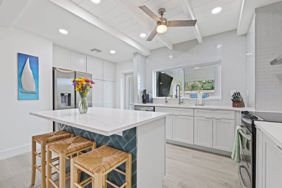 Spacious and stylish kitchen featuring a sleek island with seating, modern appliances, and a seamless flow to the outdoor space.