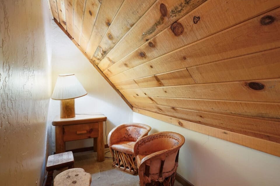 A peaceful attic retreat with chairs, a side table, and a lamp casting a soft light.