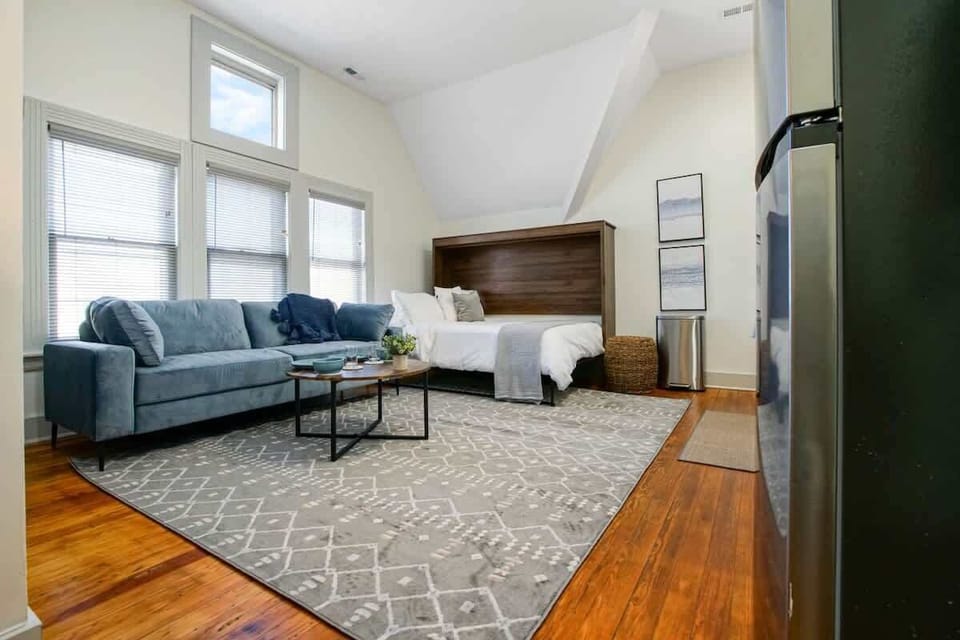 Bright open studio w/ bed, sofa seating & high windows creating an airy feel
