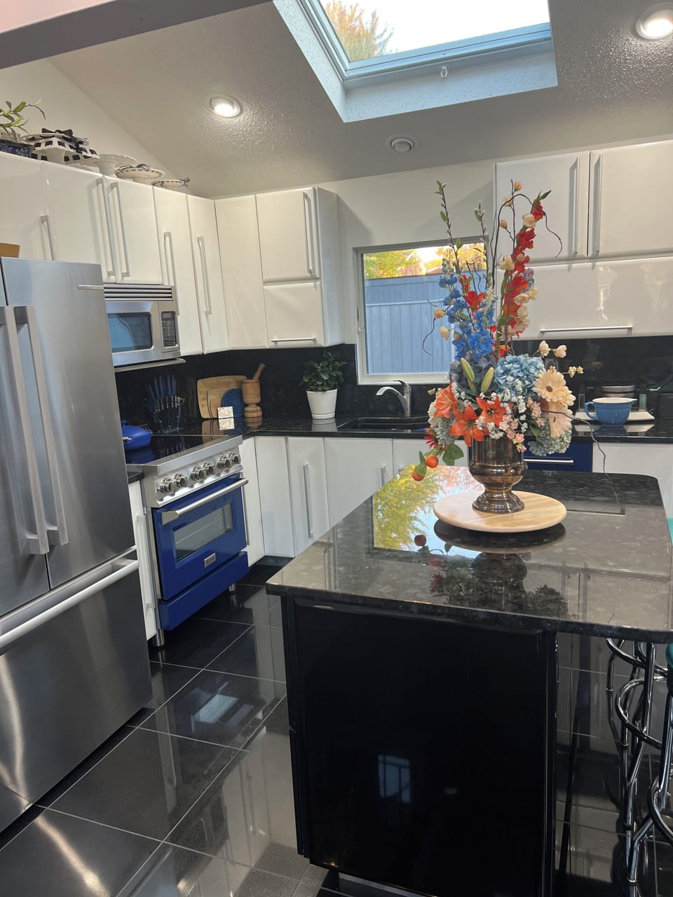 Kitchen has blue induction stove, blue dishwasher, blue pots and pans, plus.
