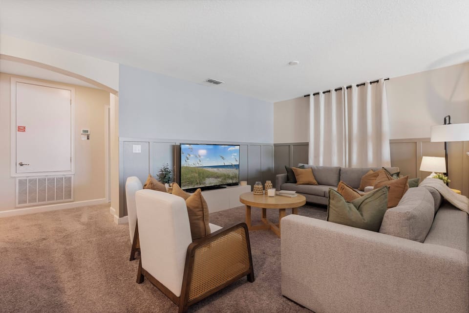 Welcome to our cozy living room, where warm beige and earthy tones create an inviting atmosphere. Unwind on the plush sectional, gather around the circular coffee table, and soak in the natural light streaming through the large.