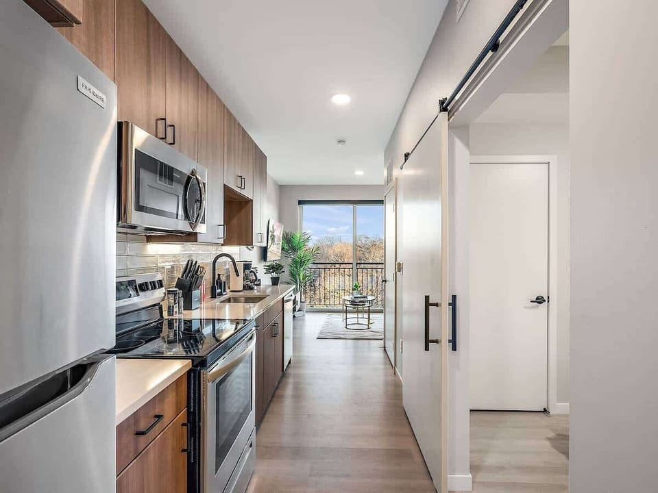Modern kitchen with stainless steel appliances, sleek finishes, and balcony views.